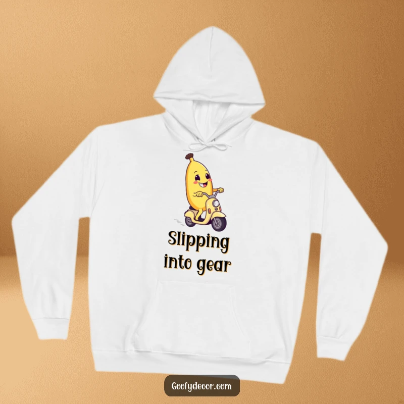 Funny hoodie depicting a grinning banana character speeding along on a tiny scooter, a symbol of cheerful motion.