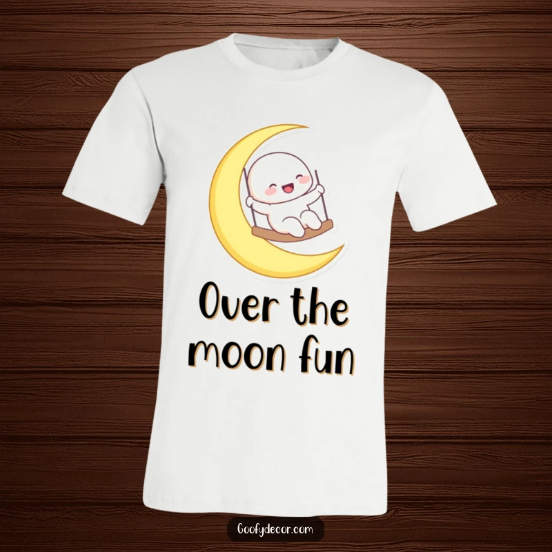 Funny laughing moon character gleefully swinging on a crescent moon, featured on a t-shirt for celestial joy.